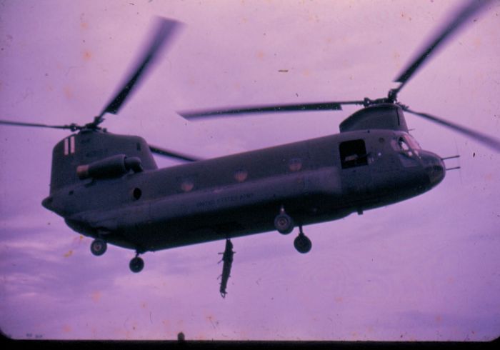 Date unknown: Operating at an unknown location, 64-13159 conducts training on loading an injured solider on a stretcher via the lower rescue door on the bottom of the helicopter (Vietnam era).