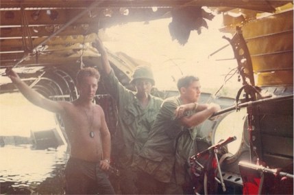 Soldiers peer out the hole in the side of Chinook 66-00120.