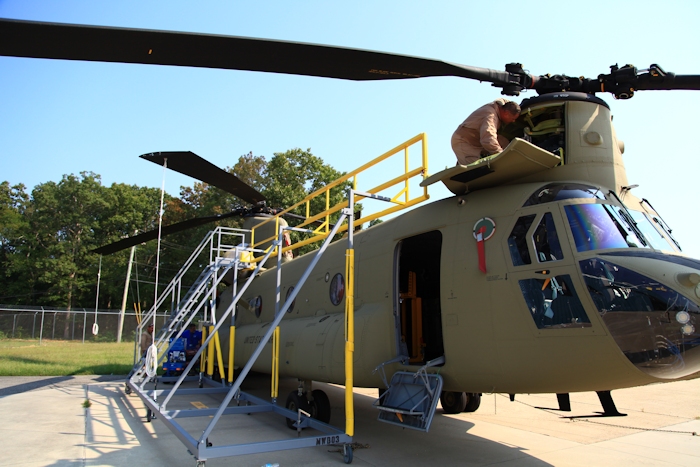 11 September 2013: CH-47F Chinook helicopter 12-08106 rests on the ramp at the Boeing Millville facility, Millville Municipal Airport (KMIV), New Jersey, awaiting movement to the Port of Baltimore for ship transport to the Republic of Korea. CH-47F New Equipment Training Team (NETT) Maintenance Test Pilot Rich Felter preflights the forward pylon.