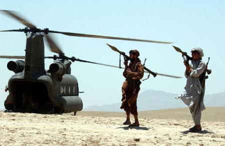 Local Afghan gunmen holding rocket propelled grenades (RPG) guard an American Chinook helicopter.