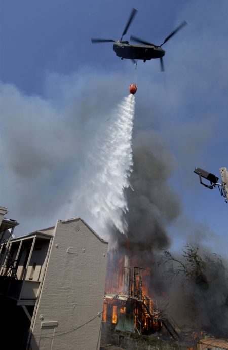 6 September 2005: The crew of a CH-47 Chinook helicopter uses a water basket to drop water on two house fires in downtown New Orleans, Louisianna. The Chinook was part of a joint military and civilian effort to assist firefighters on the ground fighting the blazing house fires.