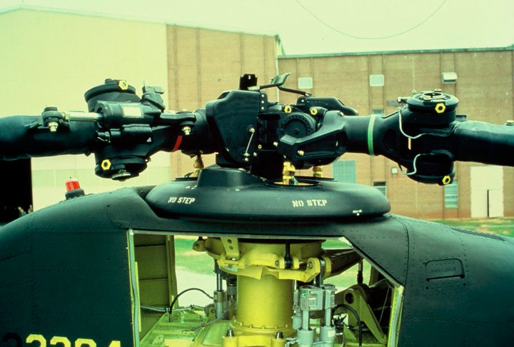 A photograph showing what the H-47 Aft Rotor Head Droop Stop Shrouds look like when installed. These shrouds were designed to prevent ice from building up on the droop stop assemblies that could otherwise jam the mechanism and prevent the stops from positioning properly on engine shutdown. In that event, the aircraft would incur serious damage.